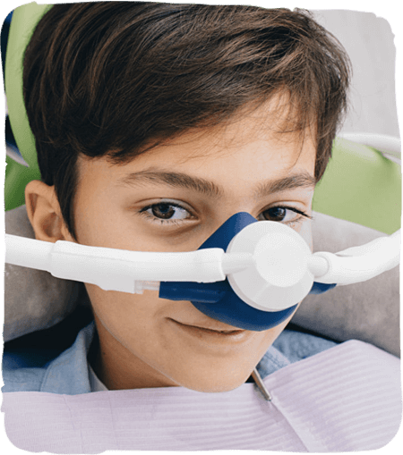 Young boy wearing protective dental equipment and mask in pediatric dental office setting.