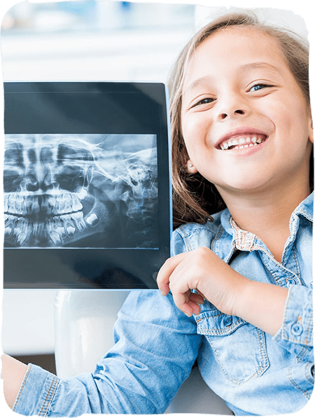Happy child holding dental X-ray in pediatric dental office setting.